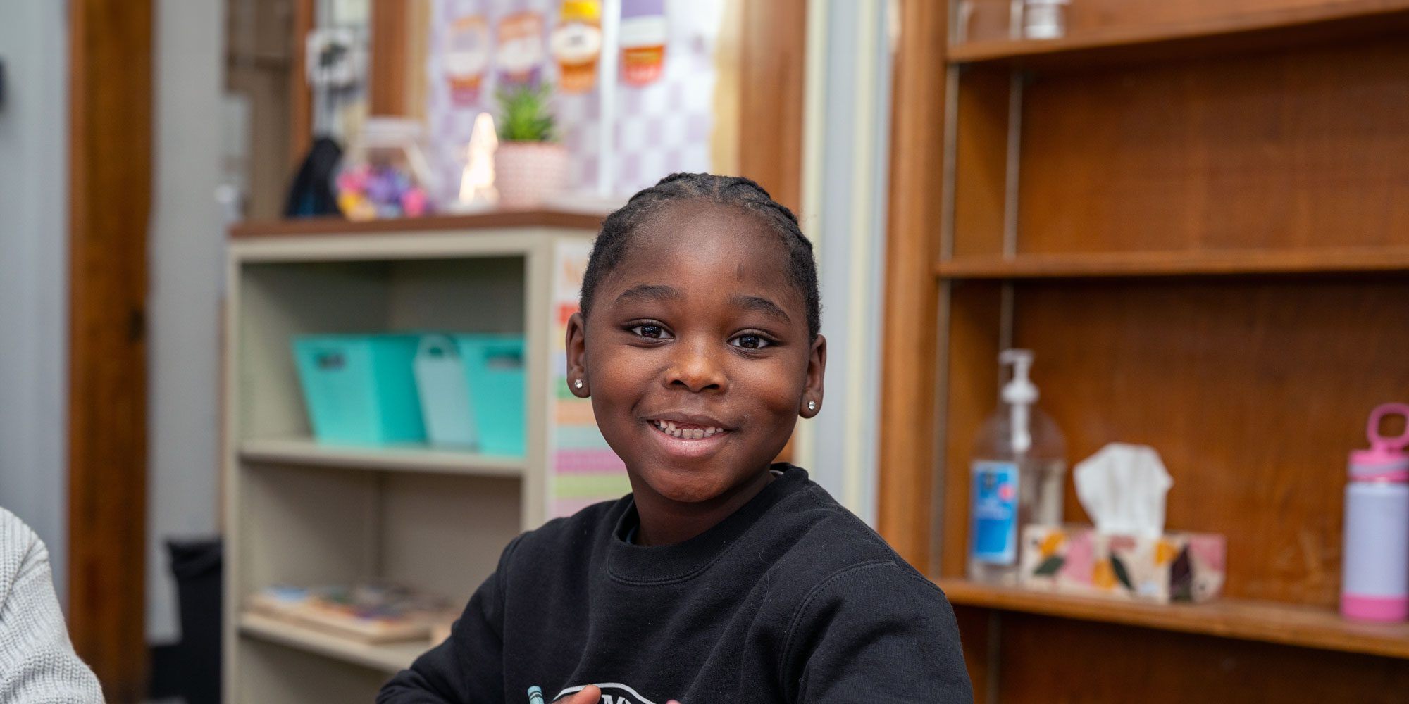 Smiling student in a classroom with bookshelves in the background.